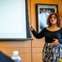 woman pointing up at her presentation on a projector as she is presenting